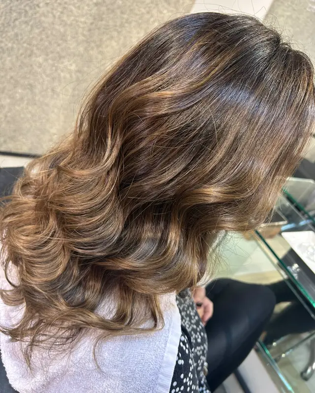 A mesma morena iluminada tonalizada e hidratada, com brilho e ondas definidas, depois do atendimento na Cássia Lecink
