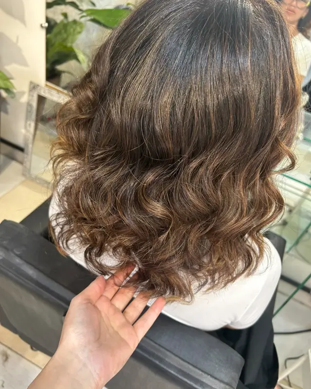 O mesmo cabelo com iluminado caramelo distribuído e onda definida, depois do atendimento na Cássia Lecink